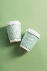 disposable paper cup with coffee on green background