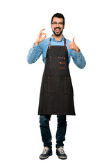 Full-length shot of Man with apron showing ok sign and thumb up gesture over isolated white background