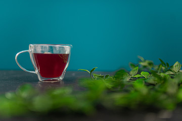 Cup of red tea on a marble desk with leaves around it