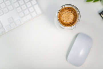 Top down cup of coffee on a white desk with computer keyboard and mouse