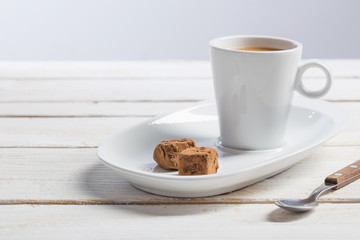 cup of coffee with chocolate candy on white old wooden table
