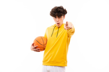 Fototapeta premium Young basketball player man over isolated white wall surprised and pointing front