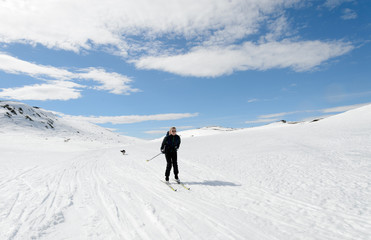 Fototapeta na wymiar Girl easter time skiing in norwegian mountains with dog