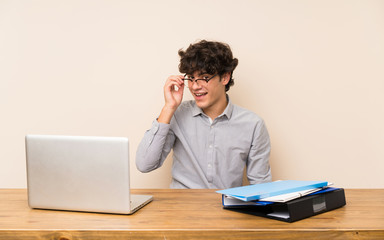 Young student man with a laptop with glasses and surprised