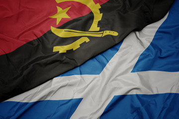 waving colorful flag of scotland and national flag of angola.