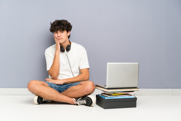 Young man with his laptop sitting one the floor unhappy and frustrated