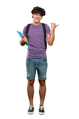 A full-length shot of a Young student man pointing to the side to present a product over isolated white background