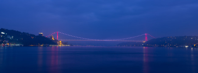 Panoramic dawn at Fatih Sultan Mehmet Bridge. Dark blue sky and lights reflected in the sea Bosphorus -, Turkey