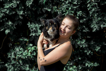Naklejka na ściany i meble Portrait of happy young woman with her cute dog