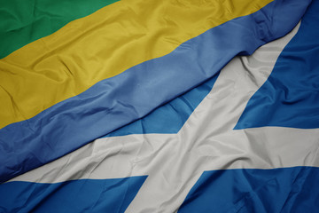 waving colorful flag of scotland and national flag of gabon.