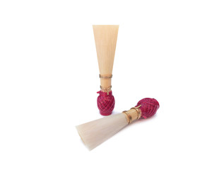 Double reed for bassoon with red thread on a white background. Two mouthpieces for wind musical instruments with a light shadow.