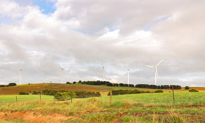 An array of large wind turbines moving to create kinetic energy for renewable energy supply on a...