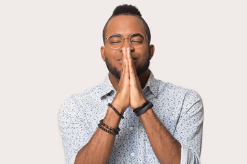 Hopeful biracial man with hands in prayer hope for luck