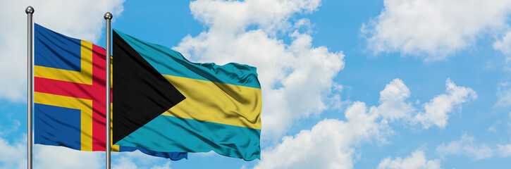 Aland Islands and Bahamas flag waving in the wind against white cloudy blue sky together. Diplomacy concept, international relations.