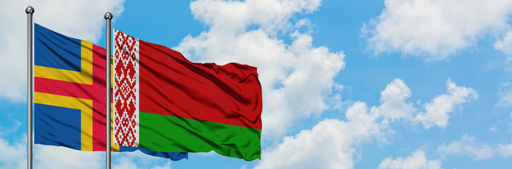 Aland Islands and Belarus flag waving in the wind against white cloudy blue sky together. Diplomacy concept, international relations.