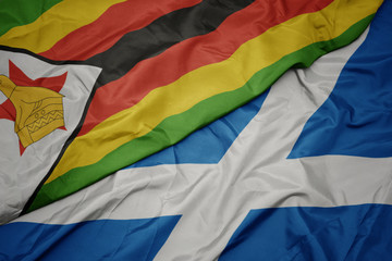 waving colorful flag of scotland and national flag of zimbabwe.