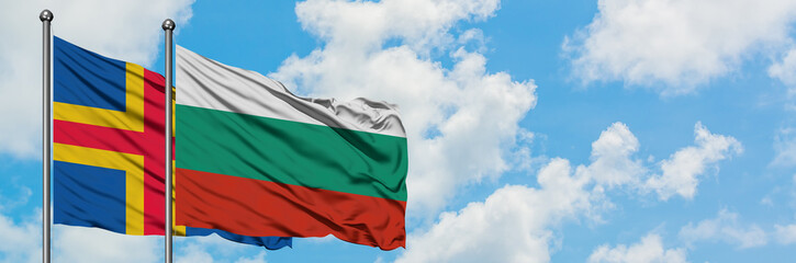 Aland Islands and Bulgaria flag waving in the wind against white cloudy blue sky together. Diplomacy concept, international relations.