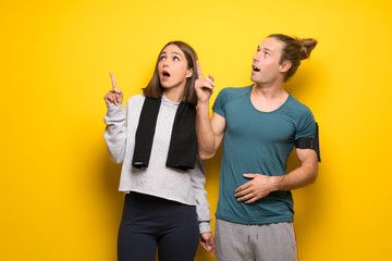 Group of athletes over yellow background pointing up and surprised