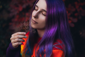Teenager with violet hair in colorful sweater.