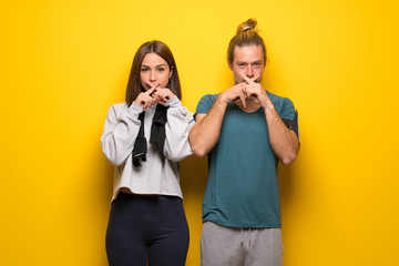 Group of athletes over yellow background showing a sign of silence gesture