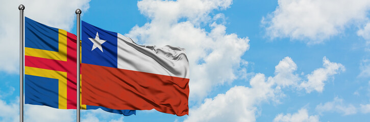 Aland Islands and Chile flag waving in the wind against white cloudy blue sky together. Diplomacy concept, international relations.
