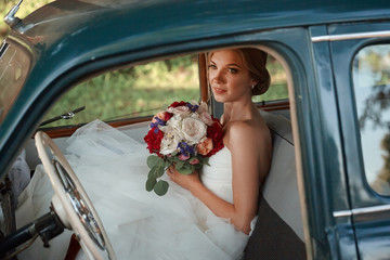 beautiful bride with wedding bouquet sitting in the car.