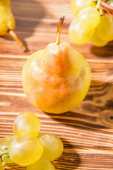 Autumn. Pear on a wood table next to grapes.