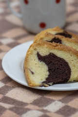 Gugelhupf on white plate on picnic blanket, very tasty edible two-colored Czech sweet cake called babovka, sliced ready to eat