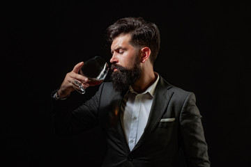 Stylish elegant bearded man Bartender holds whiskey glass. Sommelier tastes expensive alcohol drink.