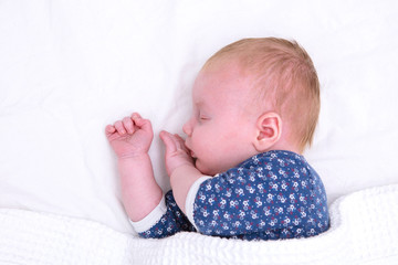 Newborn baby asleep on a white sheet. Cute young baby