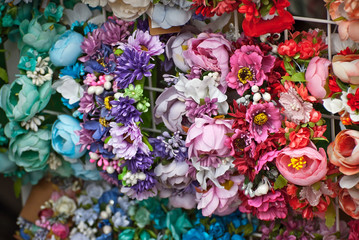 Bouquets of artificial flowers are sold at the fair. Corollas of colored small flowers. Closeup of...