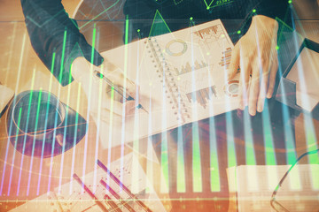 Double exposure of hands making notes with forex chart huds. Stock market concept.