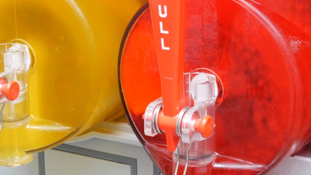 Iced juice machine juicer containing row of red and yellow slushes being prepared in slush machines on street food market