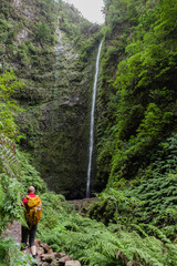 Tourist male hiking to reach "Caldeirao Verde" waterfall at footpath of "Caldeira Verde", Santana, Madeira island, Portugal