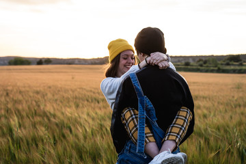 Happy young couple dressed casual in a sunset. Girl and guy kissing
