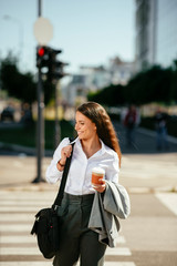 Fototapeta premium Portrait of young woman walking on the street with coffee