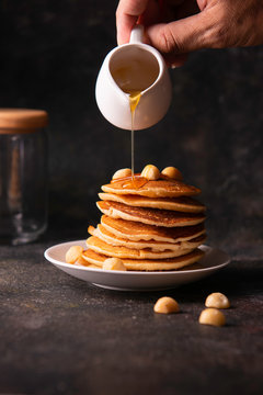  Pouring maple syrup on tasty pancakes . Close up in lighting studio .