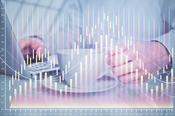 Double exposure of graph with man typing on computer in office on background. Concept of hard work.