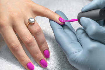 Woman getting her nails painted at beauty salon.