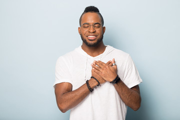 Grateful african American man keep hands at heart praying