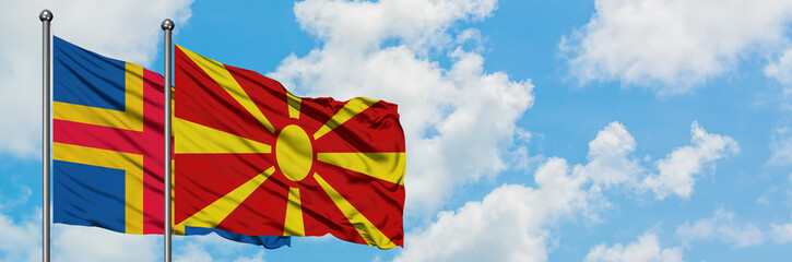 Aland Islands and Macedonia flag waving in the wind against white cloudy blue sky together. Diplomacy concept, international relations.