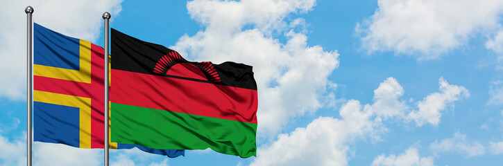 Aland Islands and Malawi flag waving in the wind against white cloudy blue sky together. Diplomacy concept, international relations.