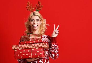 happy young cheerful girl laughs and jumps in christmas hat and with  gift on  red   background.