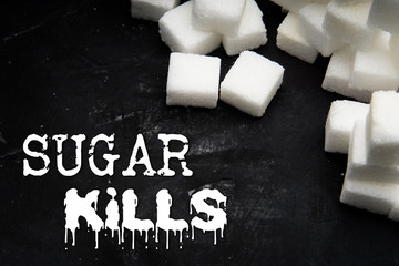 Sugar kills concept. Stacks of sugar cubes on a dark background with 