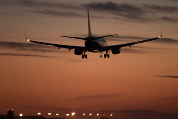 Fototapeta na wymiar Airplane silhouette landing at the airport during sunser, Barcelona