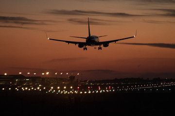 Fototapeta na wymiar Airplane silhouette landing at the airport during sunser, Barcelona