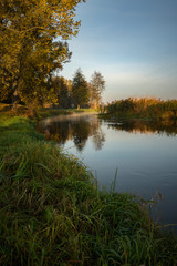 Fototapeta na wymiar Quiet river flowing through beautiful autumn landscape in Belarus
