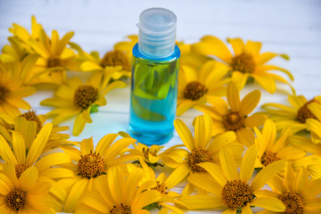 yellow flowers and blue tonic in a bottle on a wooden light background