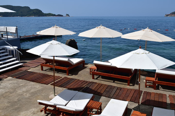Fototapeta na wymiar beach in resort area with white umbrellas in Budva, Montenegro
