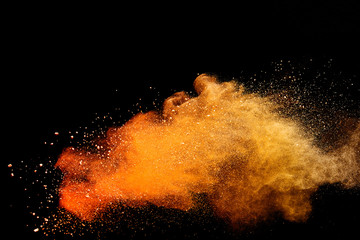 Abstract orange powder explosion isolated on black background.